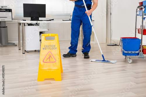 Janitor Cleaning Floor With Mop In Office