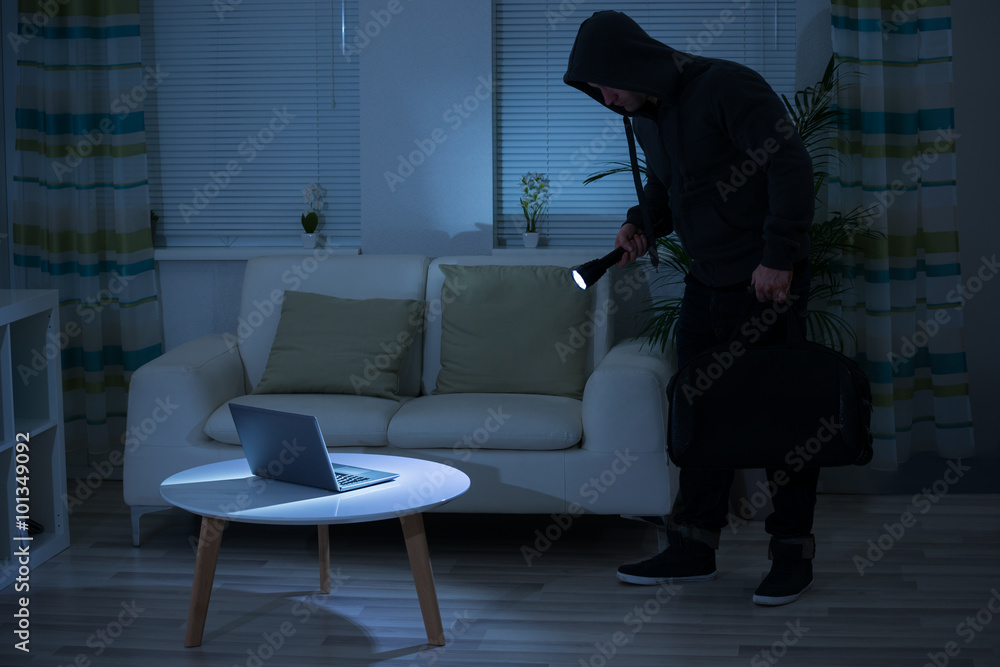 Fotografie Robber Holding Flashlight Over Laptop At Home