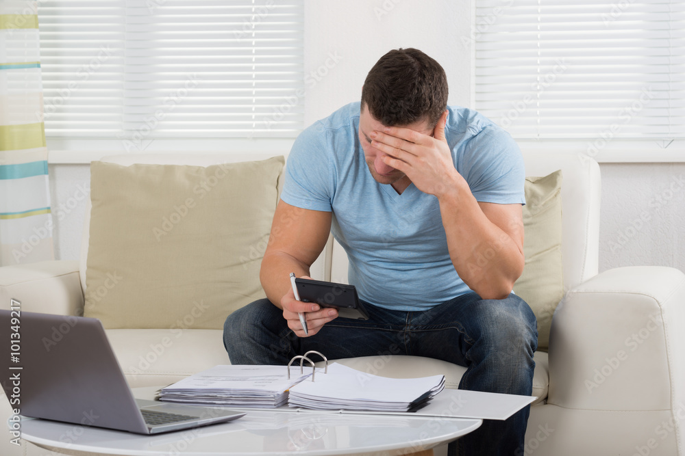 Worried Man Calculating Home Finance At Table Worried Man Calculating Home Finance At Table