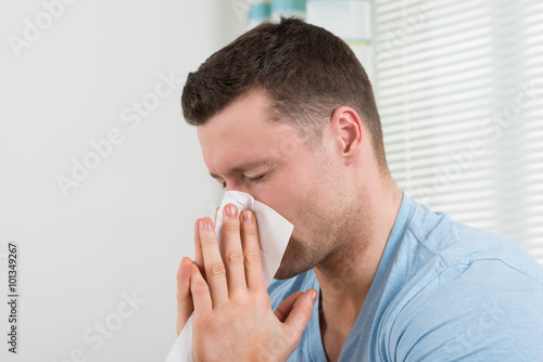 Man With Cold Blowing His Nose At Home