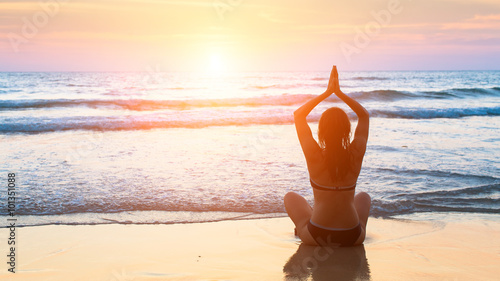 Silhouette meditation yoga woman on the background of the sea and amazing sunset. Yoga silhouette.