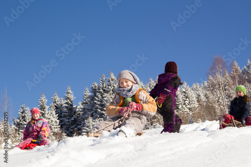 Happy children sledding at winter time. Group of children spendi