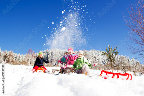 Happy children sledding at winter time. Group of children spending a nice time in winter together.