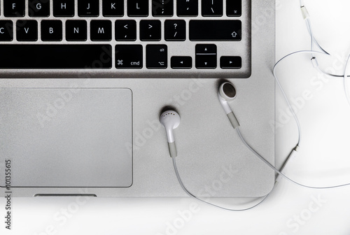 Top view of the keyboard of the laptop on white Desk with headphones