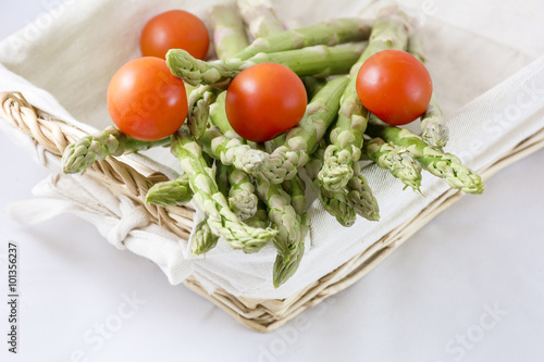Red cherry with green asparagus in the white basket