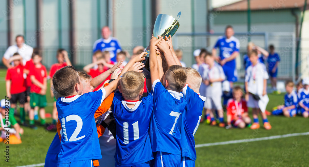 Young Sport Team with Trophy. Boys Celebrating Sports Achievement. Young Soccer Players Holding Trophy. Celebrating Soccer Football Championship. Winning team of sport tournament for kids children.