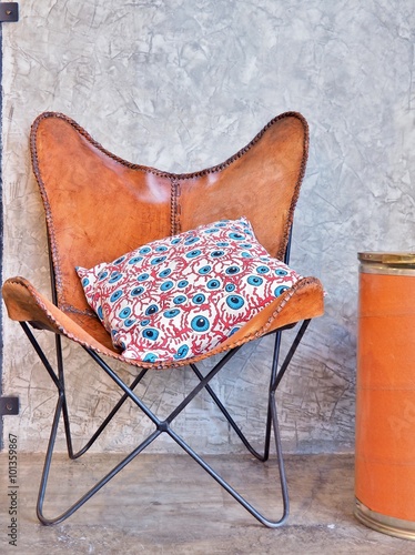 Brown Leather Armchair and Pillow in front of concrete wall, vintage style. photo