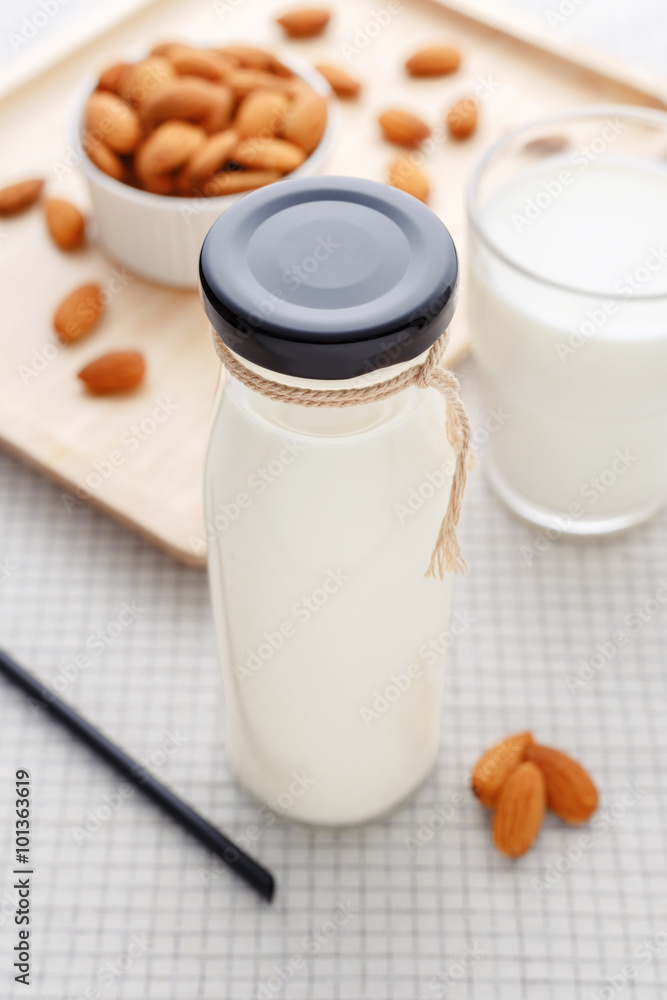 Almond milk in bottle with straw and almonds Almond milk in bottle with straw and almonds