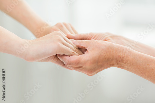 close up of senior and young woman holding hands