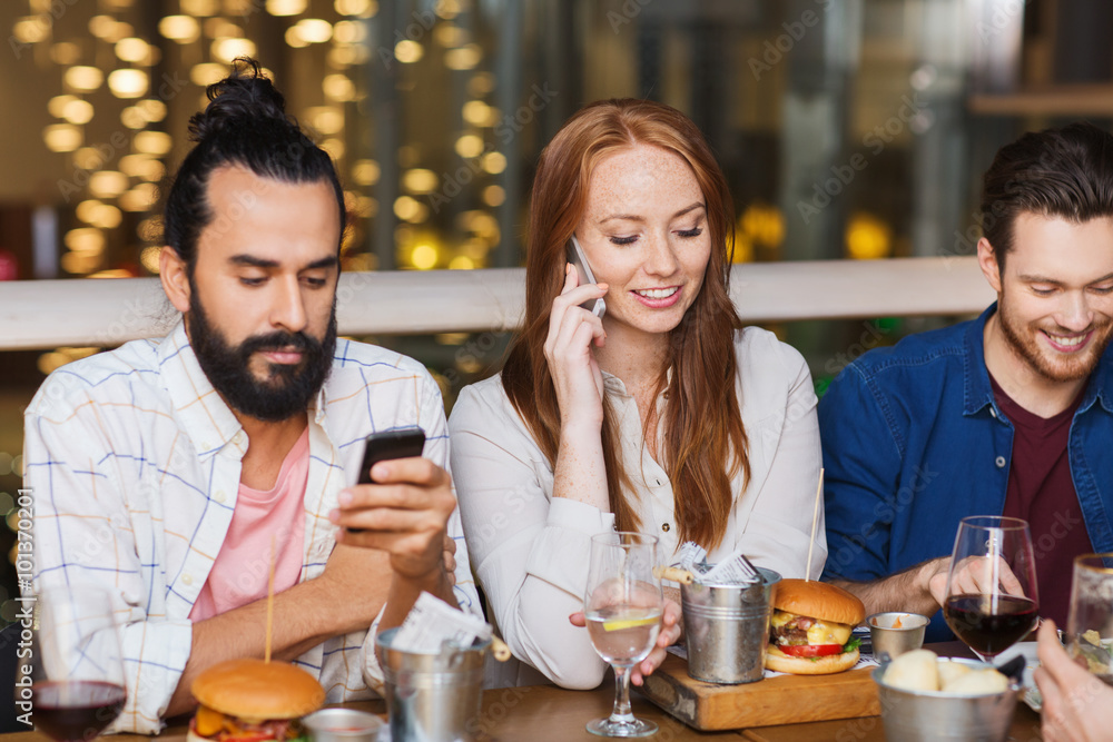 happy friends with smartphones at restaurant happy friends with smartphones at restaurant