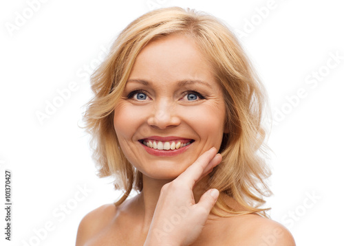 smiling woman with bare shoulders touching face