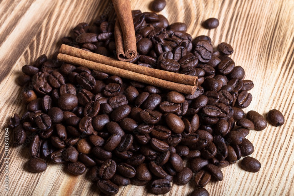 Pile of coffee beans with cinnamon on wooden table for backgroun Pile of coffee beans with cinnamon on wooden table for backgroun