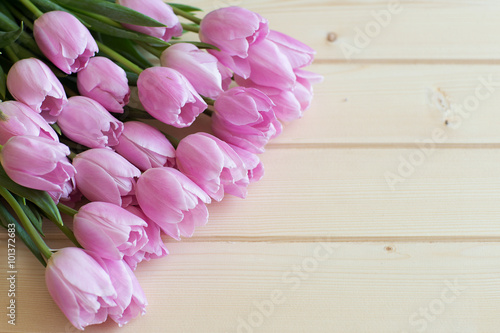 Fototapeta Naklejka Na Ścianę i Meble -  bouquet of pink tulips lie on natural wooden textur table wrapped in Kraft paper