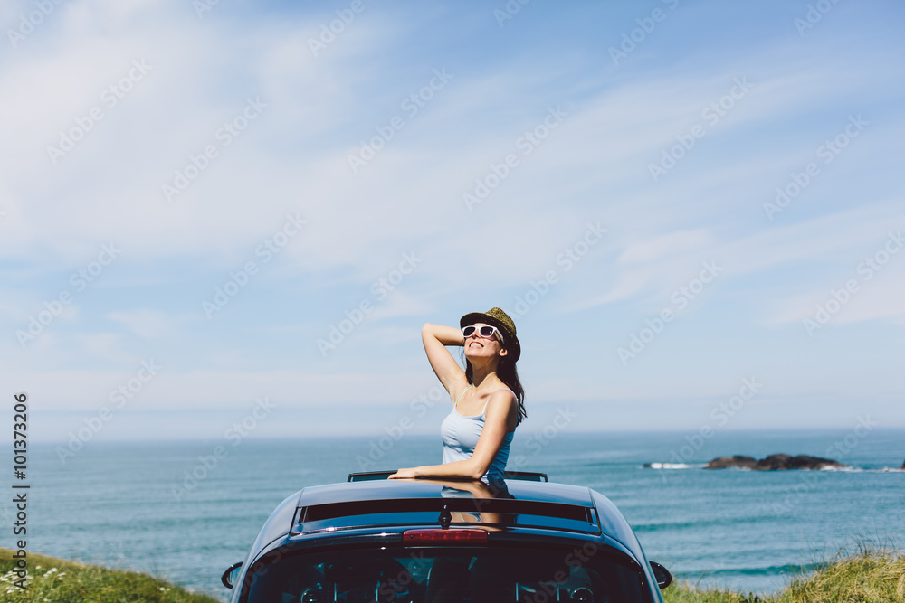 Φωτογραφία Joyful happy woman on summer travel vacation to the coast  leaning out car sunroof towards the sea and sky