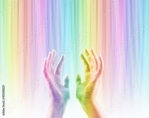 Fototapeta Naklejka Na Ścianę i Meble -  Absorbing Color Light Therapy - Female hands reaching up into rainbow colored light streaming down causing hands to become rainbow colored whilst absorbing the colored light