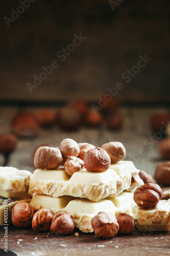 White chocolate with hazelnuts on old wooden background, selecti