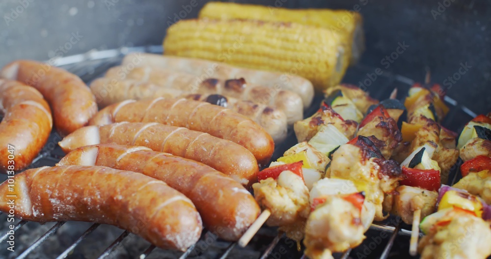 Sausages corn and vegetable kebabs grilling together on a summer BBQ or cookout in a close up view Sausages corn and vegetable kebabs grilling together on a summer BBQ or cookout in a close up view