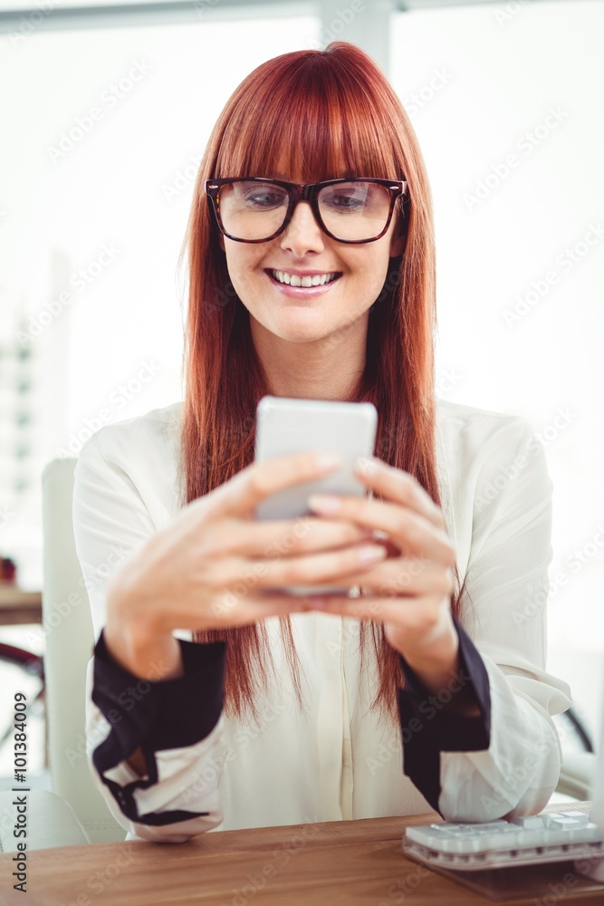 Smiling hipster businesswoman texting on her smartphone Smiling hipster businesswoman texting on her smartphone