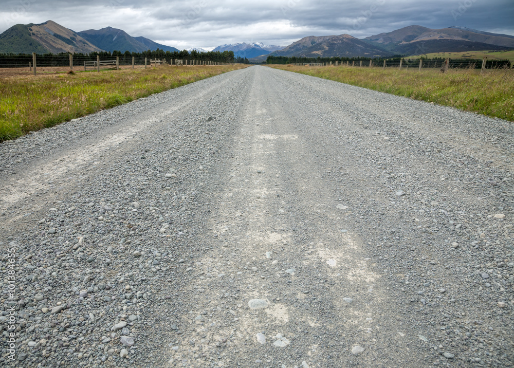 Φωτογραφία Straight gravel road through pasture in New Zealand with mountains in background