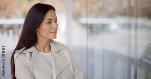 Laughing vivacious attractive young woman standing outside a store window in a town street grinning at the camera