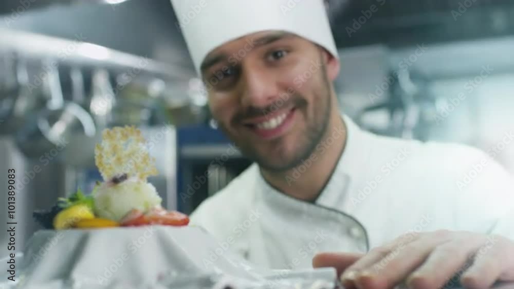 Happy professional chef in a commercial kitchen is garnishing ice cream dessert with strawberry. Shot on RED Cinema Camera. Happy professional chef in a commercial kitchen is garnishing ice cream dessert with strawberry. Shot on RED Cinema Camera.