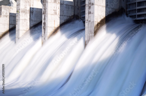 Fotografering Water rushing out of opened gates of a hydro electric power dam in long exposure
