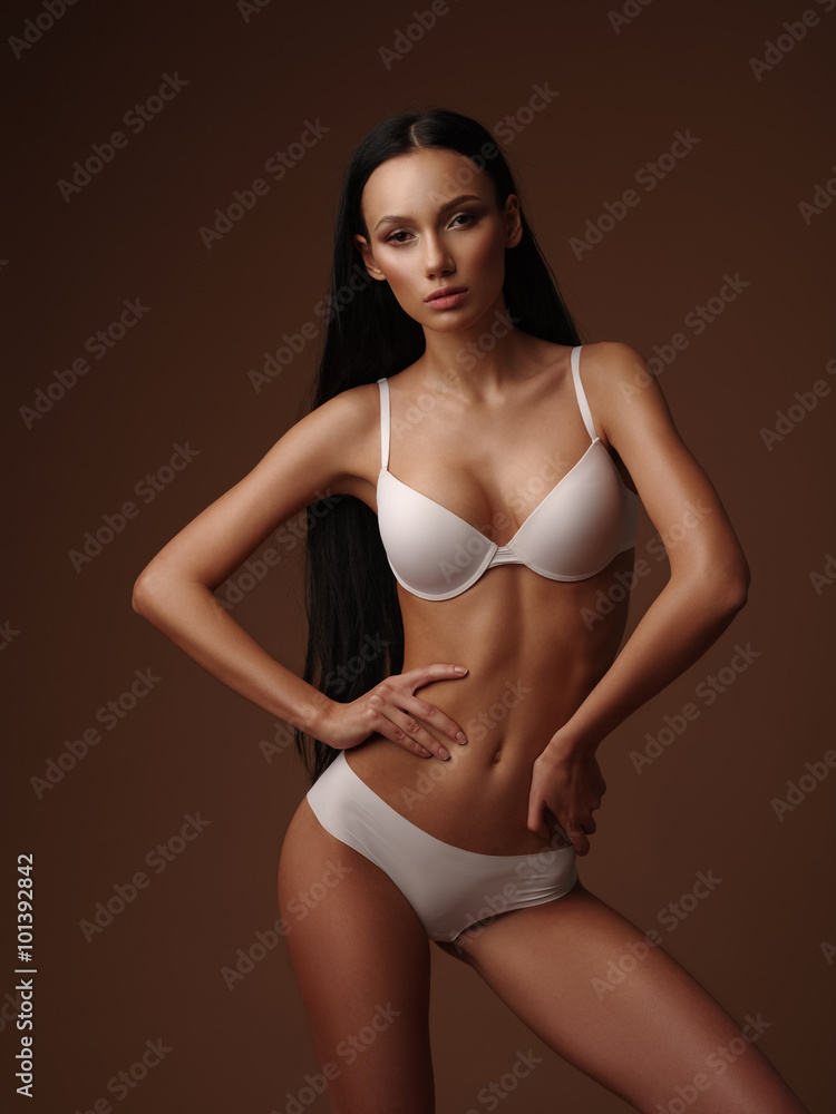 Skinny girl with black straight hair is posing in the white basic seamless  underwear collection in the studio Stock Photo | Adobe Stock