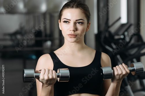 Caucasian woman lifting dumbbell in gym. She training biceps. © antgor