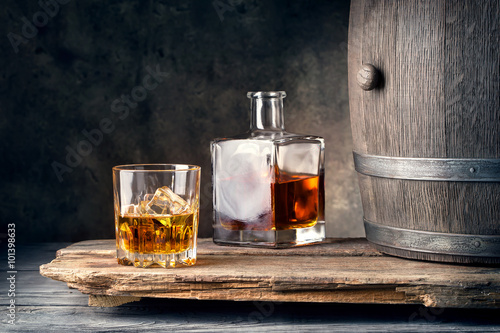 Photography Glass of whiskey with ice decanter and barrel