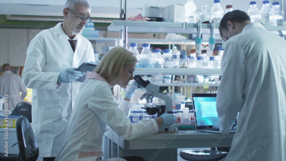 Team of scientists in white coats are working with a laptop and tablet in a laboratory. Shot on RED Cinema Camera. Team of scientists in white coats are working with a laptop and tablet in a laboratory. Shot on RED Cinema Camera.