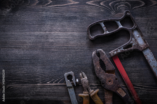 Rusty hacksaw nippers pliers on wooden board construction concep