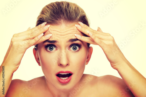 Foto A young woman checking wrinkles on her forehead