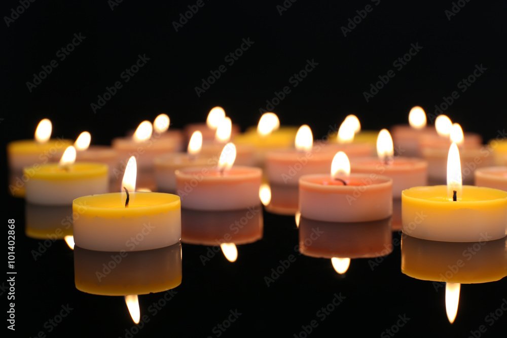 Many burning small candles on dark background, close-up Many burning small candles on dark background, close-up