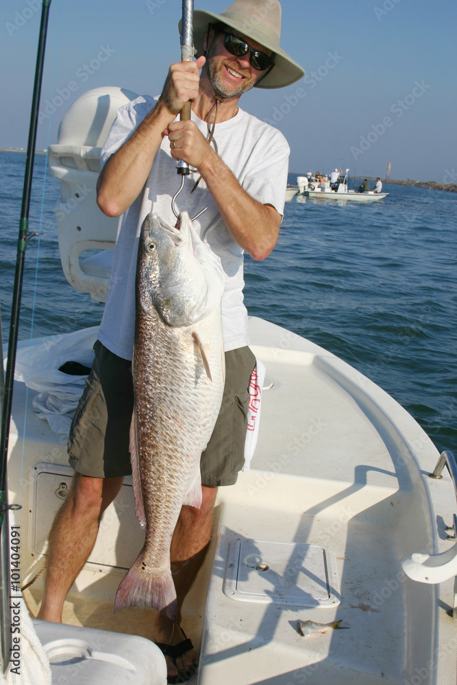 Happy fishermans holds up big redfish Happy fishermans holds up big redfish