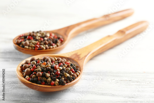Two wooden spoons with pepper on the table, close-up