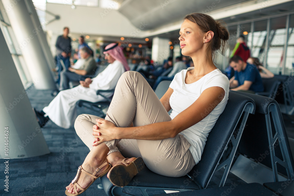 Pretty, young woman waiting at a gate area of a modern airport