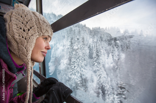 Fotografia Pretty, young woman admiring splendid winter scenery from a cabl