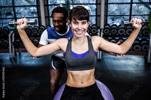 Male trainer helping woman during dumbbells exercise © WavebreakMediaMicro