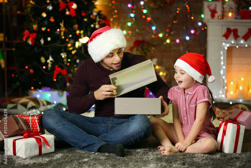 Older brother and little sister in Santa hat opening gift on Christmas background Older brother and little sister in Santa hat opening gift on Christmas background