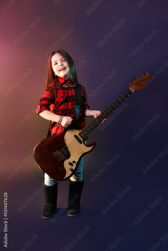Obraz premium Little rock star playing guitar on dark purple background