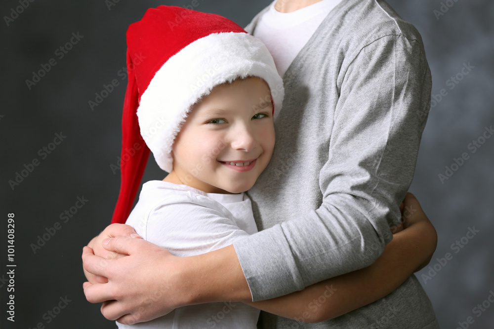 Portrait of boy in Santa hat on grey background, close up Portrait of boy in Santa hat on grey background, close up