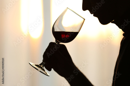 Obraz na płótnie Silhouette of man sniffing red wine in a glass, close up