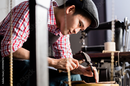 Foto Asian shoe or belt maker in his leather workshop