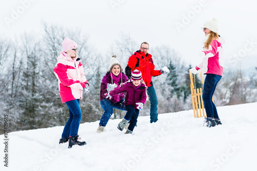 Familie mit Kindern hat Schneeballschlacht im Winter
