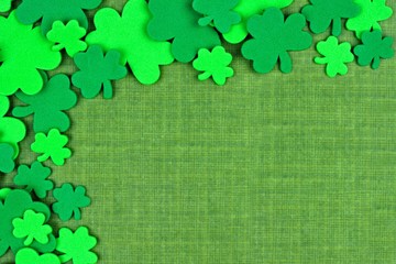St Patricks Day corner border of shamrock confetti over a green linen background