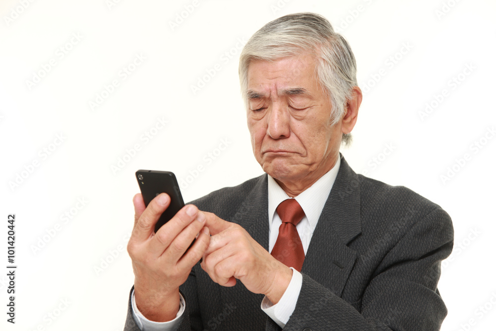 senior Japanese businessman using smart phone looking confused senior Japanese businessman using smart phone looking confused