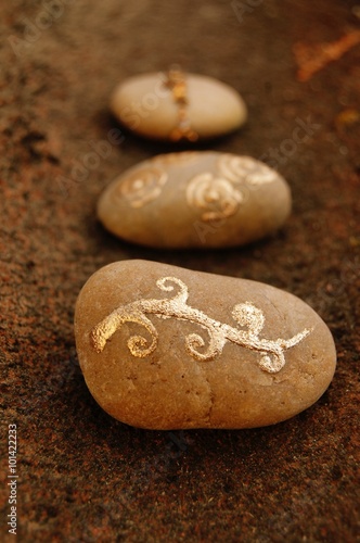 Drei bemalte Steine mit goldenen Symbolen