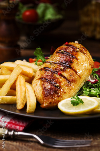 grilled chicken breast with green salad and french fries.