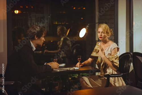 attractive lady in dress and man in suit in cafe.
