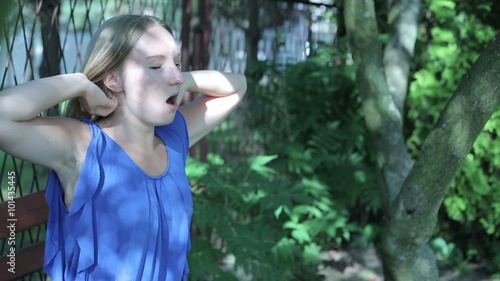 Young woman sitting outside yawning and streching arms photo